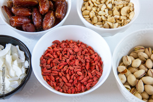 Goji berries, dates, coconut chips, pistachios and cashews in bowls. Healthy snacks.