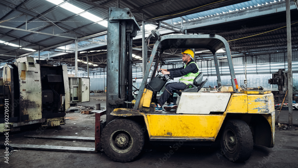 Industrial worker driving a forklift in the factory. Engineer is working and maintaining in the warehouse.