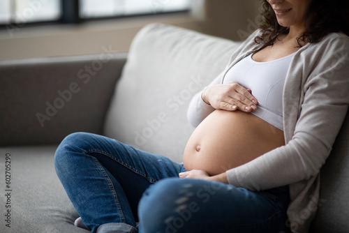 Prenatal Time. Unrecognizable Pregnant Woman Sitting On Couch And Embracing Her Belly