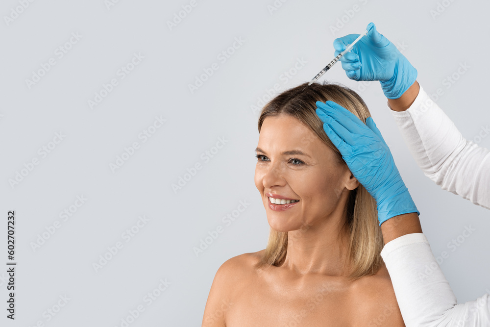 Beautician making scalp injections for blonde lady, copy space Beautician making scalp injections for blonde lady, copy space