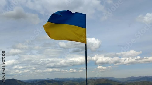 Ukraine flag waving on the top of Zahar Berkut in Carpathian Mountains, ukrainian state symbol, blue and yellow flag with cloudy sky on background.  photo