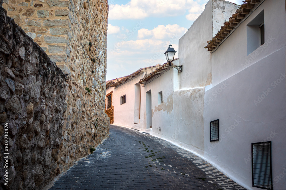 Narrow steep street in the old town of Moratalla, Murcia, Spain, with whitewashed houses and medieval wall