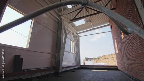 Cable in doorway of empty room with high ceiling at construction site. Incomplete public building with open facade and slopy roof photo