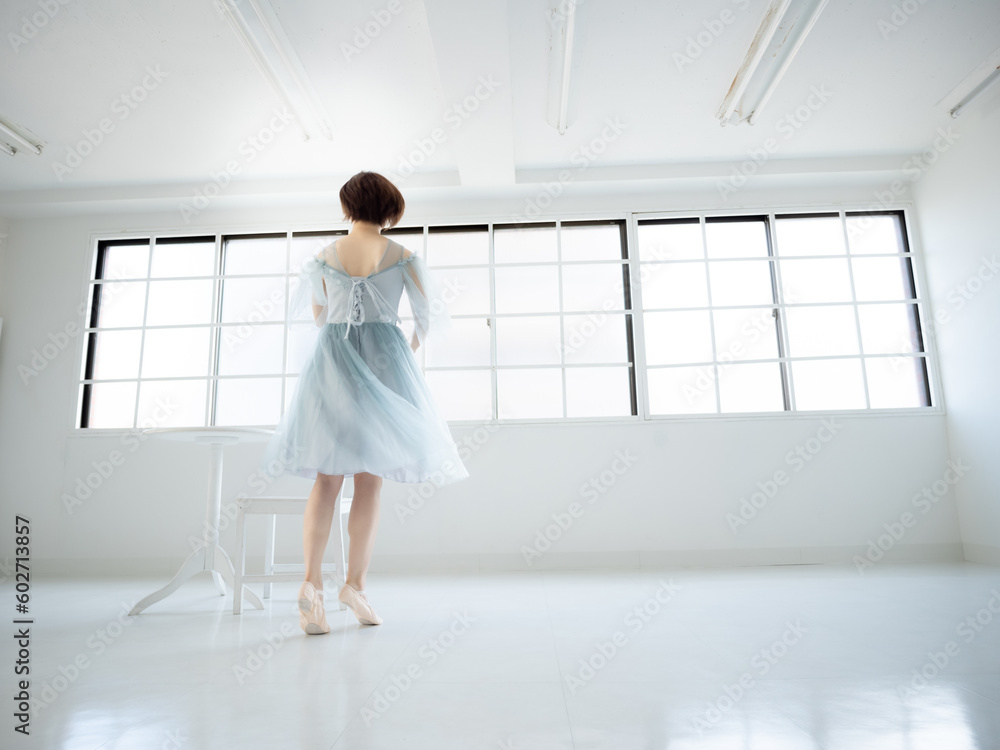 窓のある明るい室内でバレエの練習をする女性 窓のある明るい室内でバレエの練習をする女性