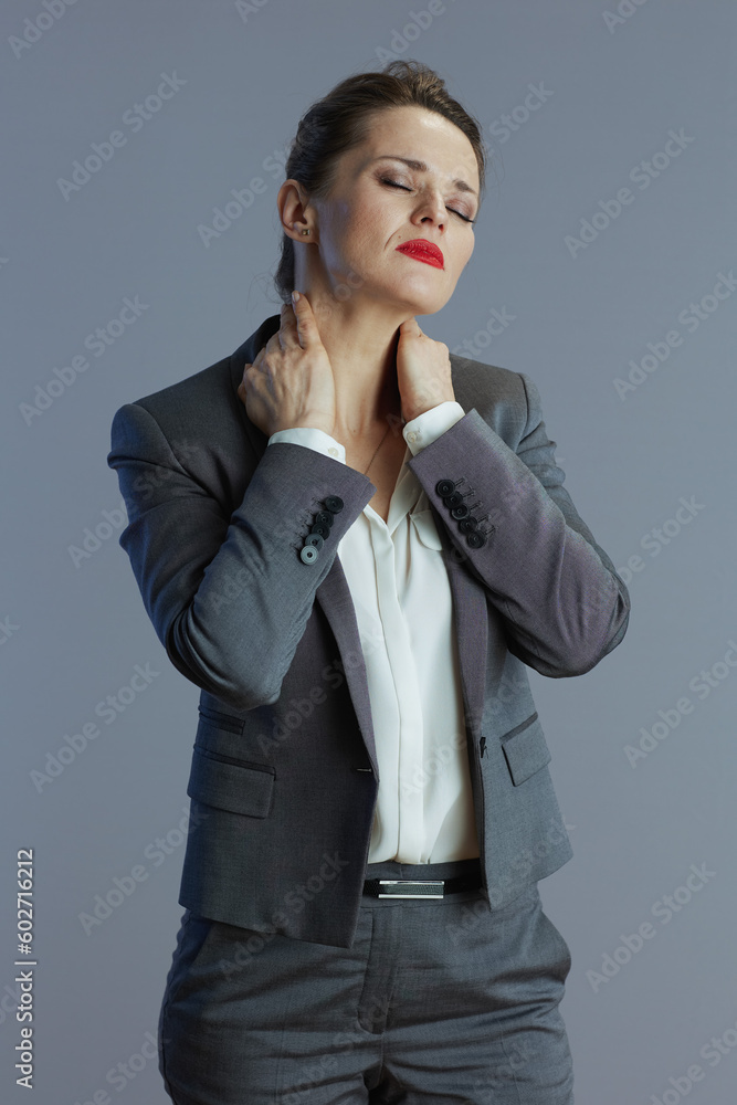 tired female worker having neck pain against gray tired female worker having neck pain against gray