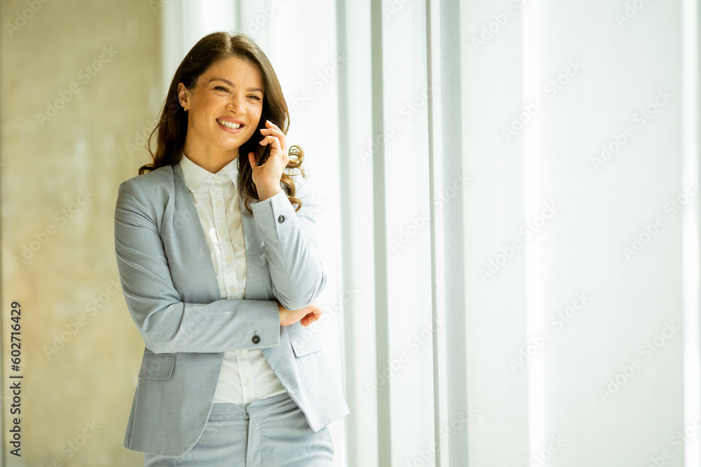 Young woman with mobile phone by the window Young woman with mobile phone by the window