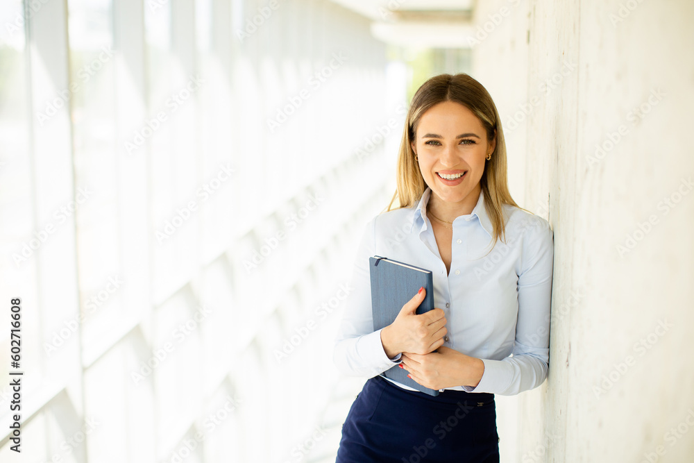 Young business woman holding with notebook in the office hallway Young business woman holding with notebook in the office hallway