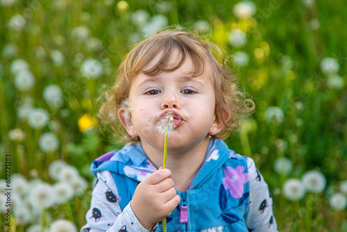 A child in nature blows a dandelion. Selective focus.