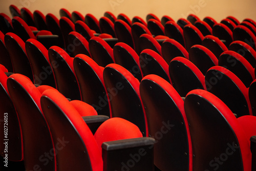 Algumas fileiras de poltronas de cor vermelha em um teatro vazio.