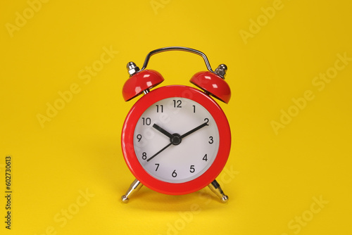 red alarm clock on yellow background