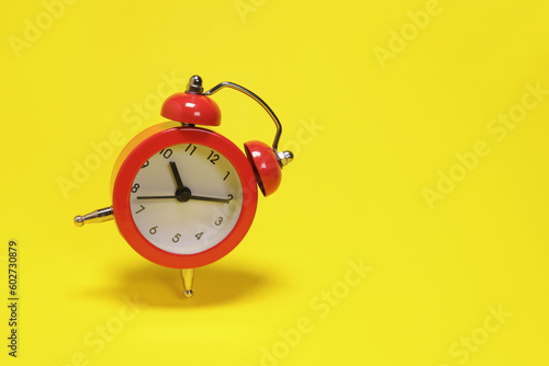 Flying red alarm clock on yellow background. copy space for text