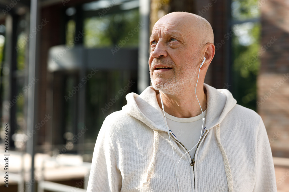 Side View of the Cool Mature Smiling Man Wearing Headphones. Sporty Positive Man Wearing Headphones Before Running. Sport And Healthy Lifestyle Concept Side View of the Cool Mature Smiling Man Wearing Headphones. Sporty Positive Man Wearing Headphones Before Running. Sport And Healthy Lifestyle Concept
