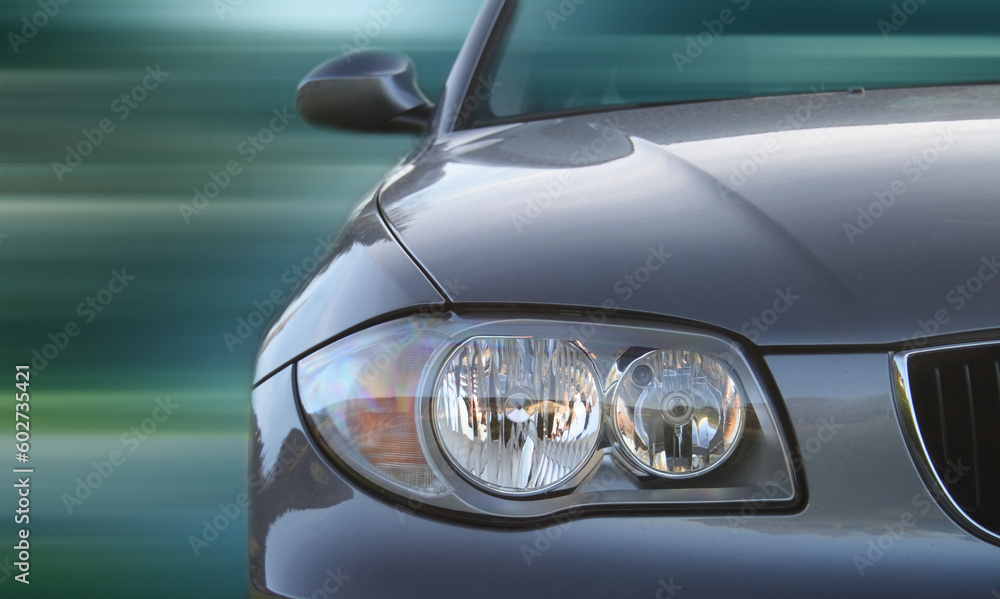 Front of a car with a blurred background. Metallic paint texture on car, not noise. Focus on lights.