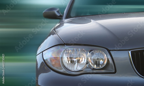 Front of a car with a blurred background. Metallic paint texture on car, not noise. Focus on lights. © Designpics