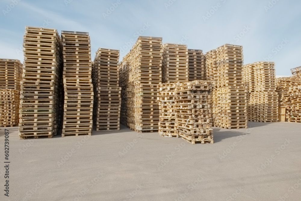 high stacks of pallets stacked on top of each other in an open-air warehouse high stacks of pallets stacked on top of each other in an open-air warehouse