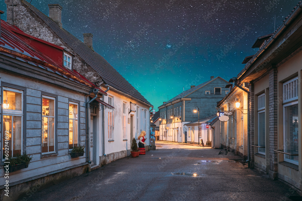 Kuressaare, Estonia. Houses At Kauba Street In Evening Or Night Illuminations. Old Traditional Houses On Narrow Street. Amazing Bold Bright Blue Starry Sky Gradient Above Houses. Azure Sky Background.