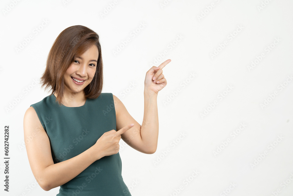 Young smiling Asian woman pointing finger sideways to copy space in pink color background. Young smiling Asian woman pointing finger sideways to copy space in pink color background.
