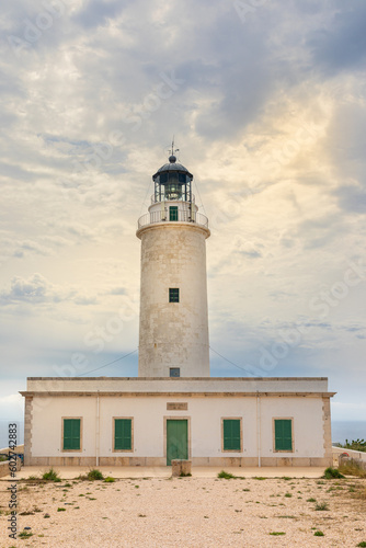 Lighthouse of La Mola, on the island of Formentera. Vertical photo on a cloudy day, with a clearing that lets in the sun's rays. Balearic Islands, Spain.
