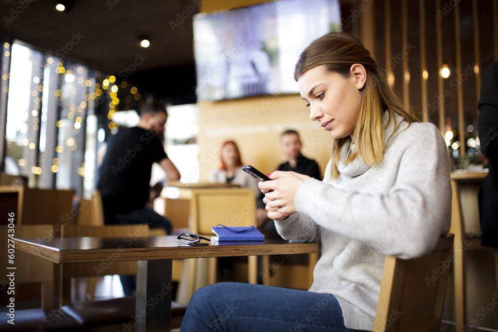 Girl at a modern cafe looking at phone. Girl at a modern cafe looking at phone.