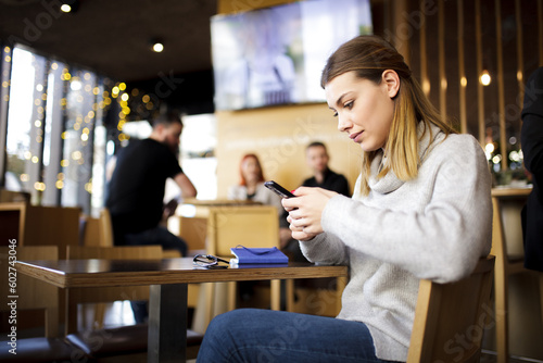 Girl at a modern cafe looking at phone.