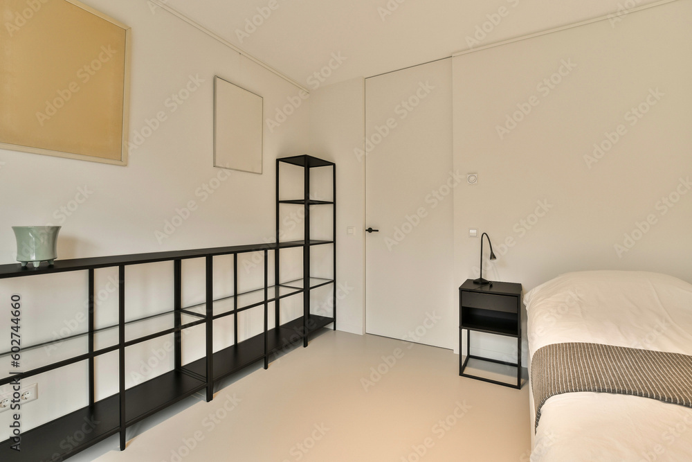 a bedroom with white walls and black shelvings on the wall next to the bed in the room is empty a bedroom with white walls and black shelvings on the wall next to the bed in the room is empty