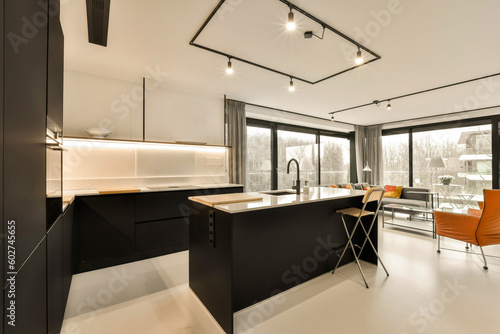 a kitchen and dining area in a modern style home with black cabinets, white flooring and an orange chair