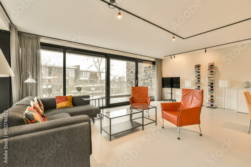 a living room with couches, chairs and a television on the wall in the center of the room is large windows