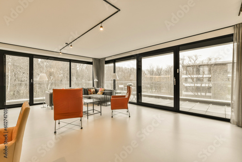 a living room with two orange chairs and a large window looking out onto the street in front of the house
