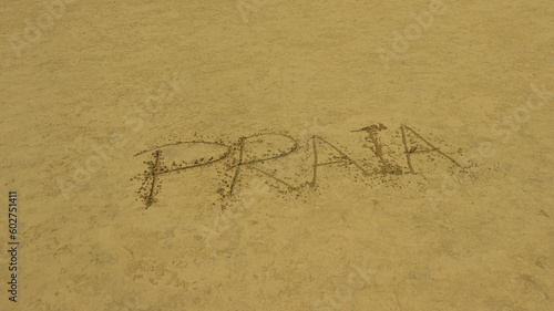 Palavra Praia escrito na areia de uma praia brasileira. 