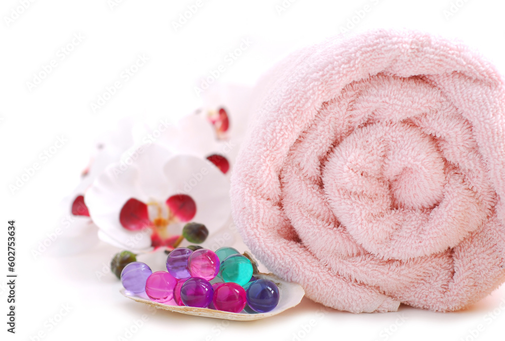 Pink rolled up towel with bath beads on white background Pink rolled up towel with bath beads on white background