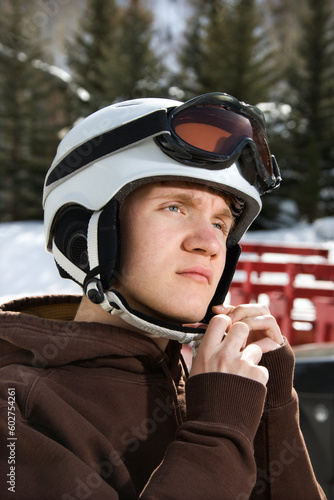 Caucasian male teenager fastening helmet.