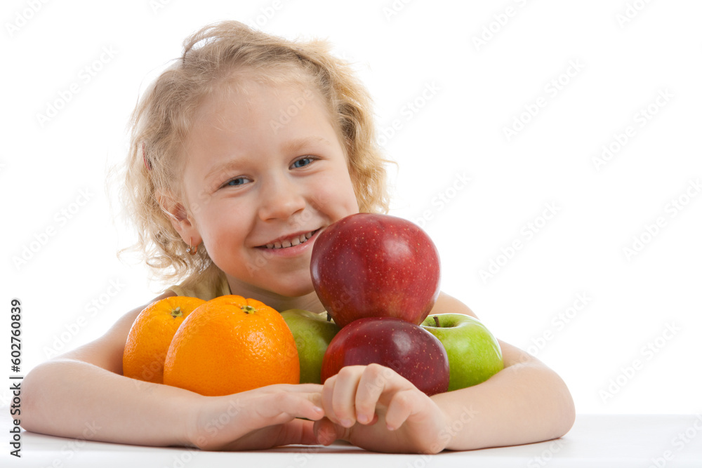 Smiling girl sits at the table with fruit heap Smiling girl sits at the table with fruit heap