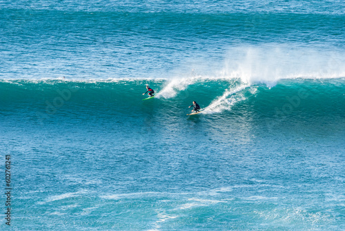 Big Waves crashing creating white foam that vaporises in the air. Sopelana beach near Bilbao. Two surfers ride the same wave together. Day of relaxation and tranquility.