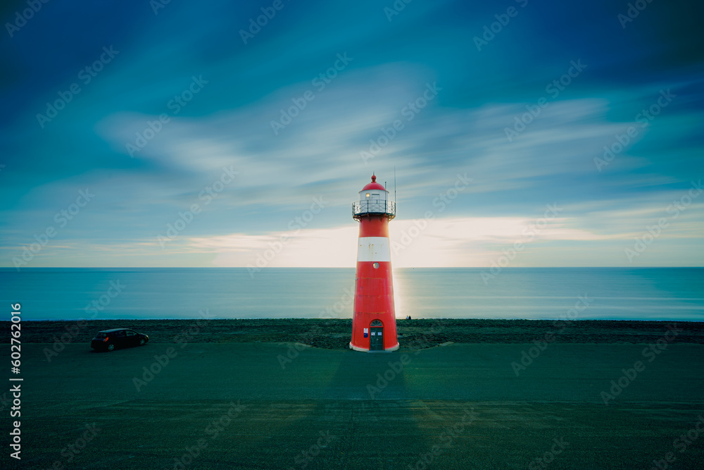 Fototapeta premium Red & white vintage lighthouse at dutch coast in west kapelle