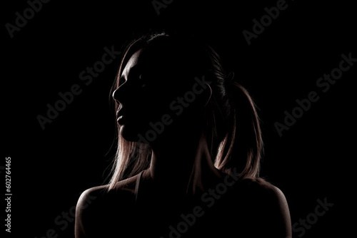 Beautiful caucasian girl posing yoga in shadow. side lit photo on black background.