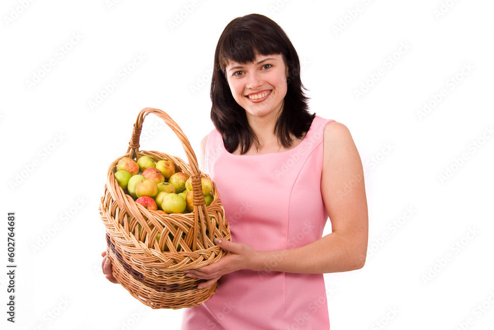 Girl in pink dress is standing and holding a basket full apples on white background. Beautiful woman holding a basket of delicious fresh fruits. Pretty girl with basket of apples. Isolated over white. Girl in pink dress is standing and holding a basket full apples on white background. Beautiful woman holding a basket of delicious fresh fruits. Pretty girl with basket of apples. Isolated over white.