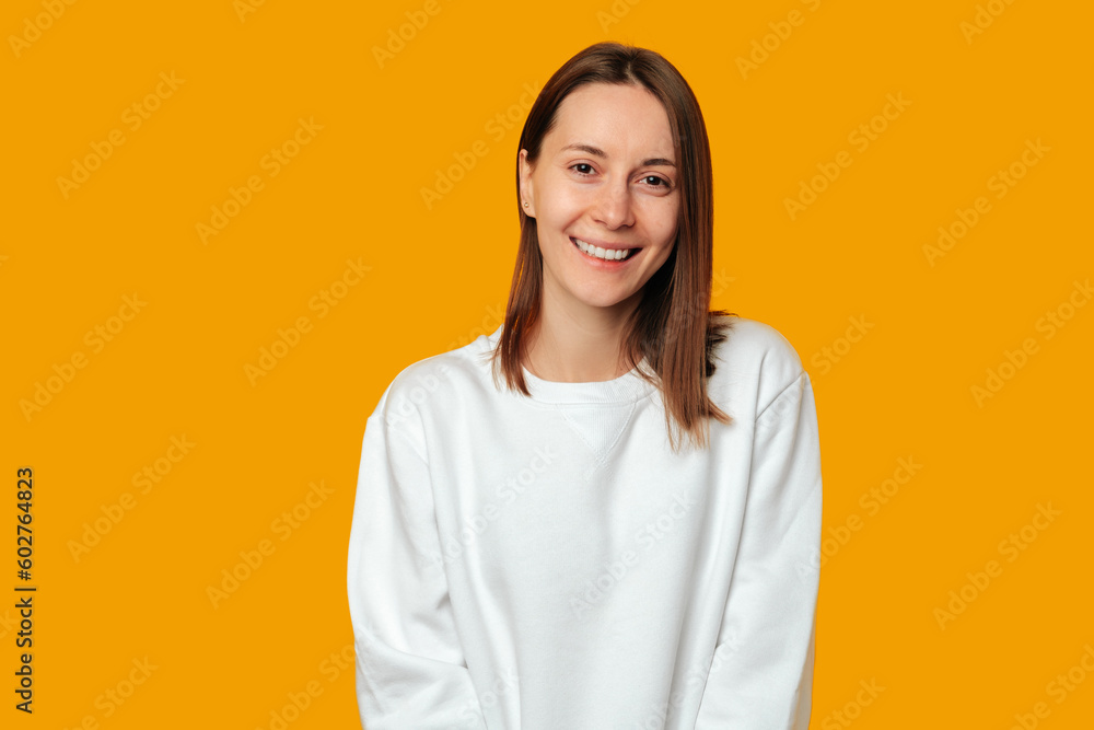 Simple studio portrait of a young modern woman who is smiling at the camera over yellow background. Simple studio portrait of a young modern woman who is smiling at the camera over yellow background.
