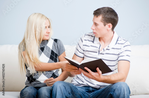 Attractive couple tussling over a book. Horizontal shot.