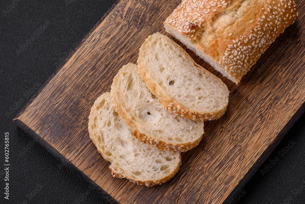 Crispy wheat flour baguette with sesame seeds on a wooden cutting board Crispy wheat flour baguette with sesame seeds on a wooden cutting board