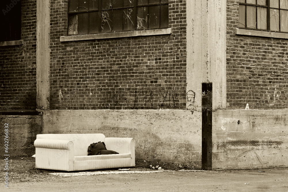 homeless living room in the city, a couch in an old industrial alley