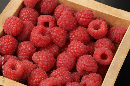 Fresh sweet raspberries in a cardboard box close-up.