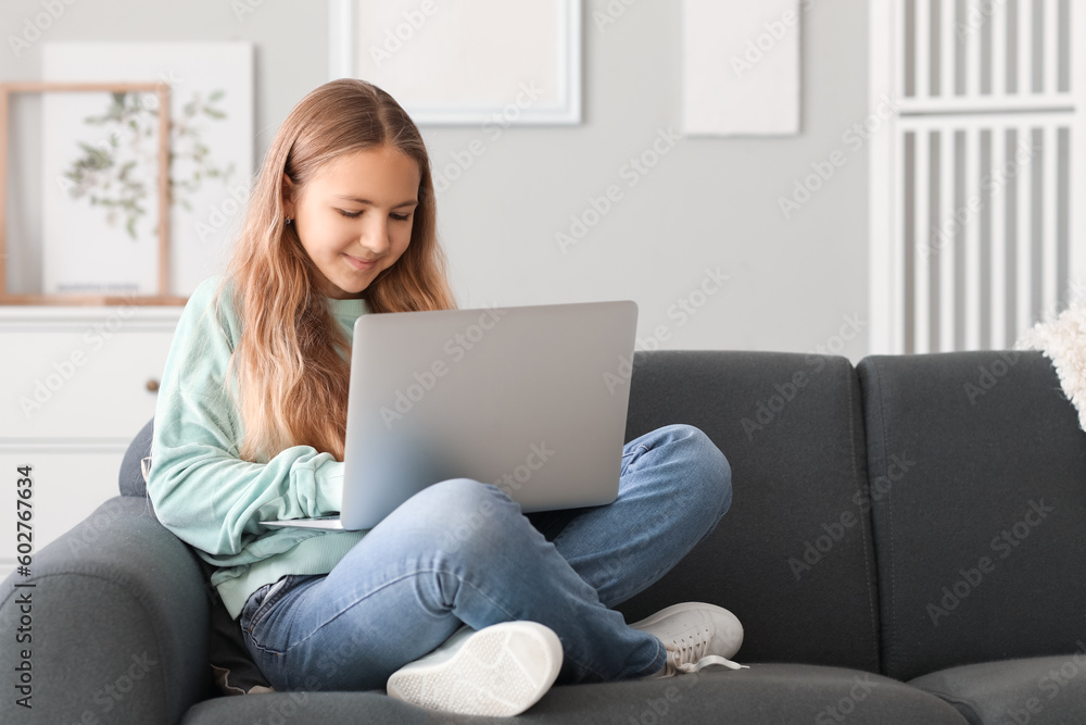 Little girl using laptop on sofa at home Little girl using laptop on sofa at home