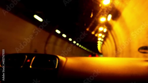 blurred video 4K dark road through mountains, car drives through long, dark, lamp-lit tunnel in swiss alps, lights flicker, go into distance, auto travel concept, traffic, light at end of tunnel photo