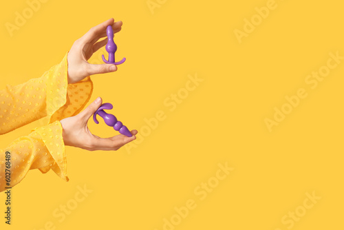 Woman with anal plugs from sex shop on yellow background