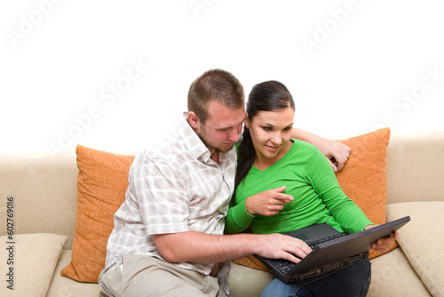 happy couple sitting on sofa together with laptop
