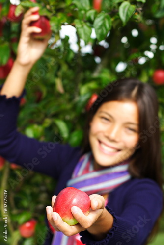Smiling autumn woman picking and giving apples from tree.