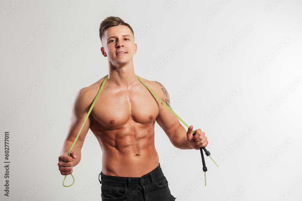 Cool handsome athletic fit man with a naked muscular torso with a jump rope on a white background. Workout and cardio Cool handsome athletic fit man with a naked muscular torso with a jump rope on a white background. Workout and cardio