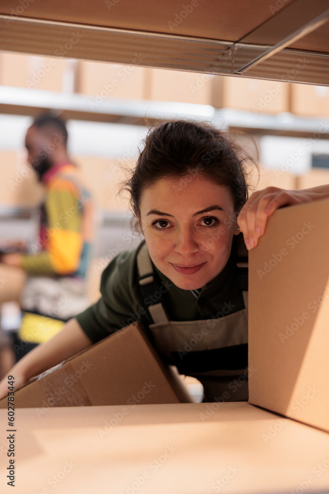 Smiling employee working with cardboard boxes, preparing customers packages in warehouse. Storage room supervisor packing parcels and managing delivery operations in storehouse Smiling employee working with cardboard boxes, preparing customers packages in warehouse. Storage room supervisor packing parcels and managing delivery operations in storehouse