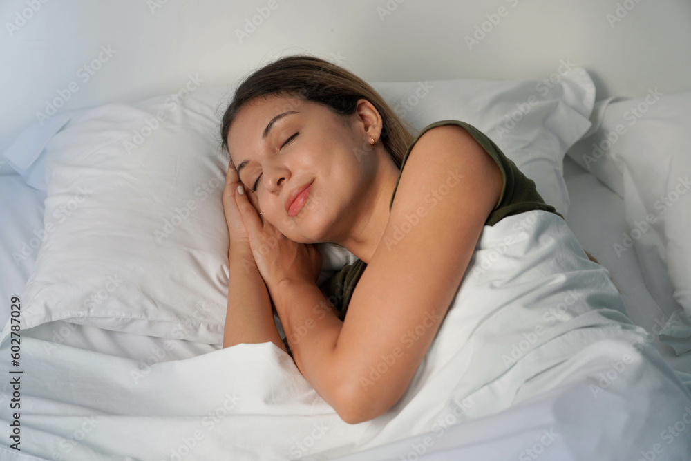 Young woman sleeping profoundly in white sheets at night Young woman sleeping profoundly in white sheets at night