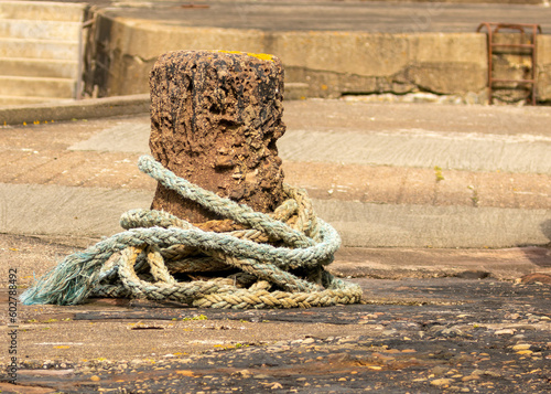 Old and historic stone pillar with rope around it for bringing boats into the harbour in Pennan, east coast of Scotland where Local Hero was filmed  photo